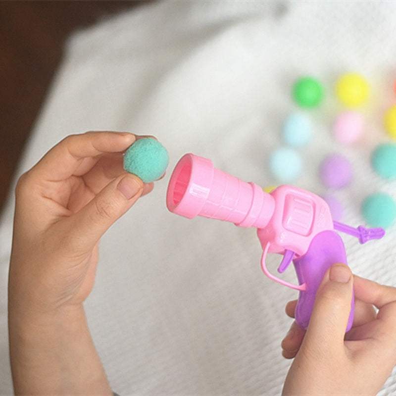 Child holding pink and purple automatic ball launcher toy with colorful balls in the background