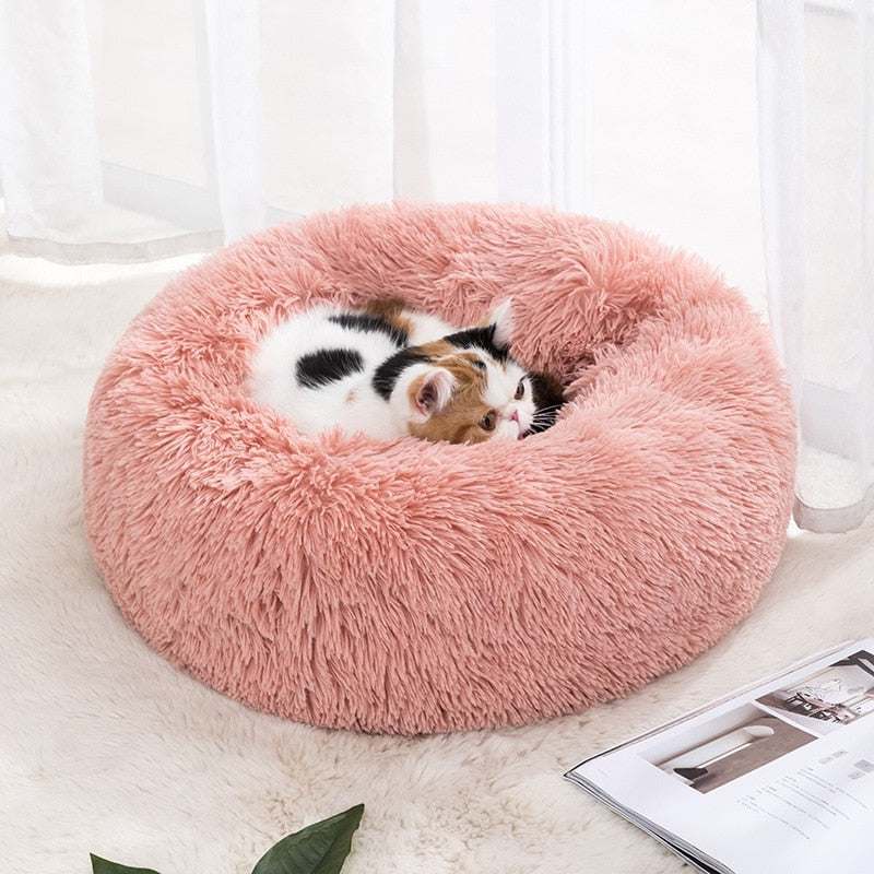 pink fluffy calming pet bed with kitten resting inside