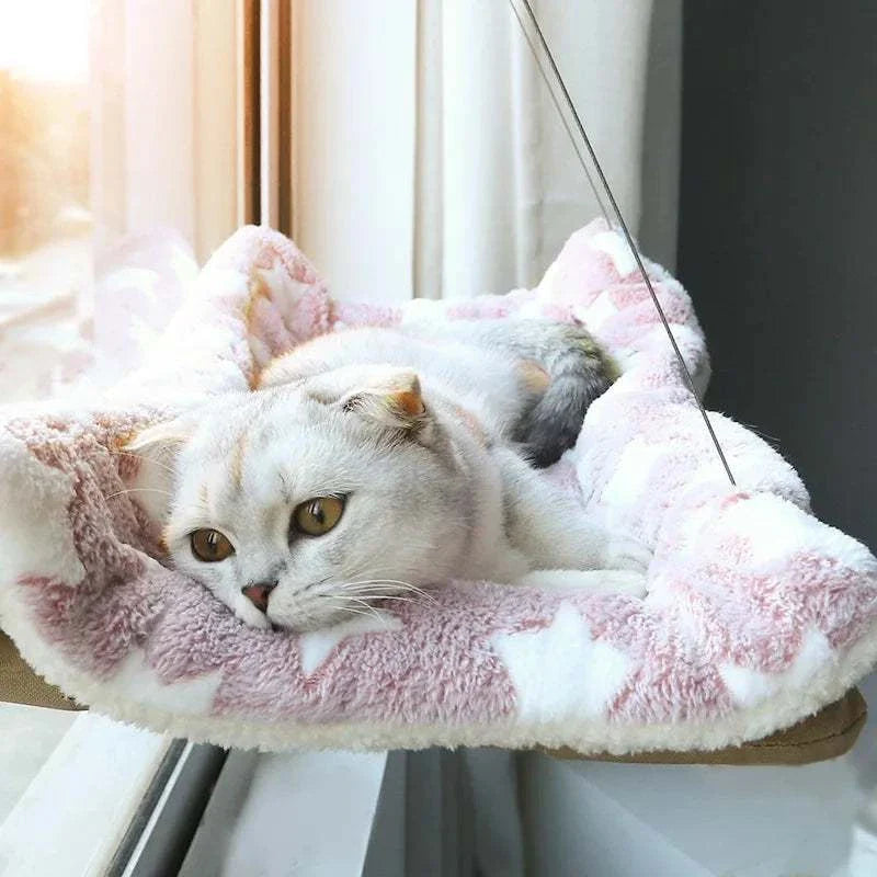 Cat resting on a soft pink and white star-patterned window mounted perch hammock