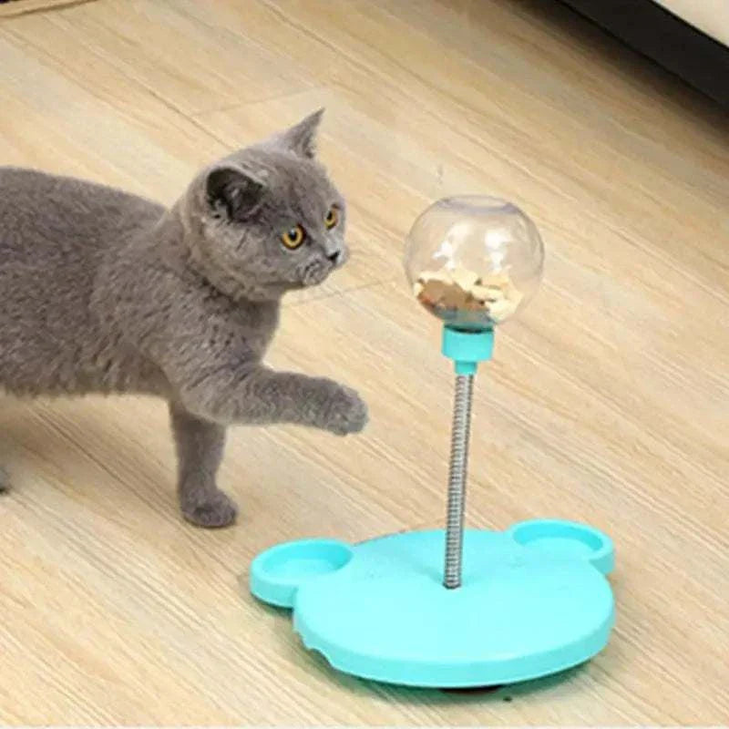 Gray cat playing with a Leaking Treats Ball pet feeder toy dispensing treats on a wooden floor