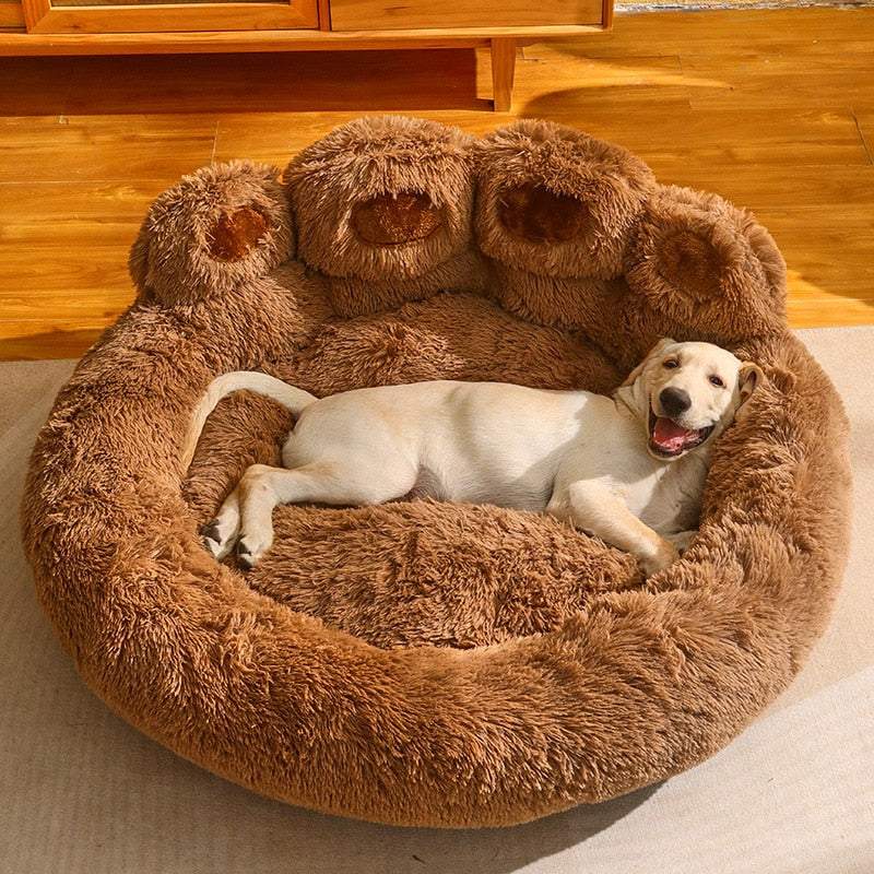 Cute brown bear paw shape pet bed with a happy dog lying inside on a wooden floor