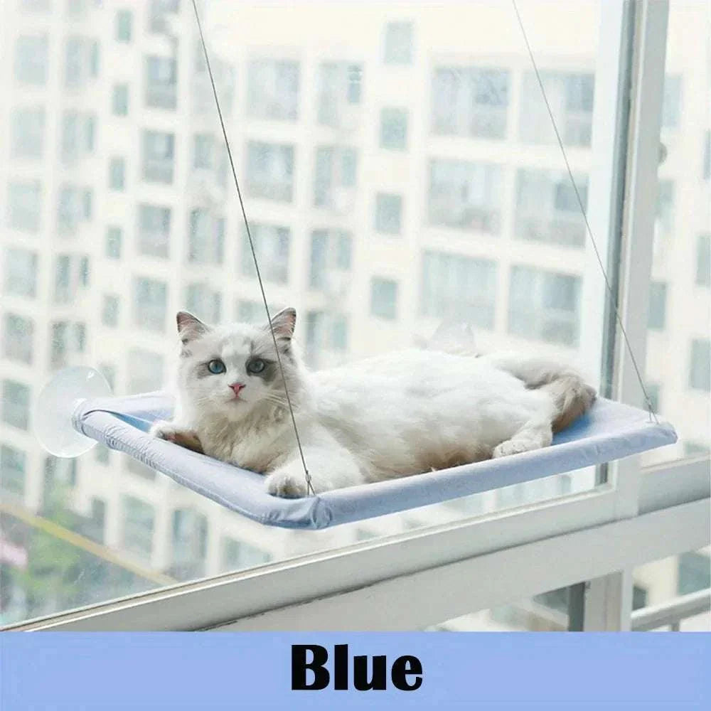 Cat window mounted perch hammock with white cat lounging on blue fabric by window